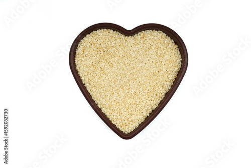 White sesame seeds in a wooden bowl. Top view. A copy of the space. heart-shaped bowl
