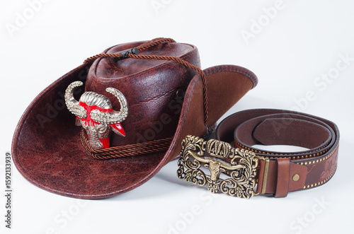 Cowboy hat with cockade and cowboy belt on a light background.