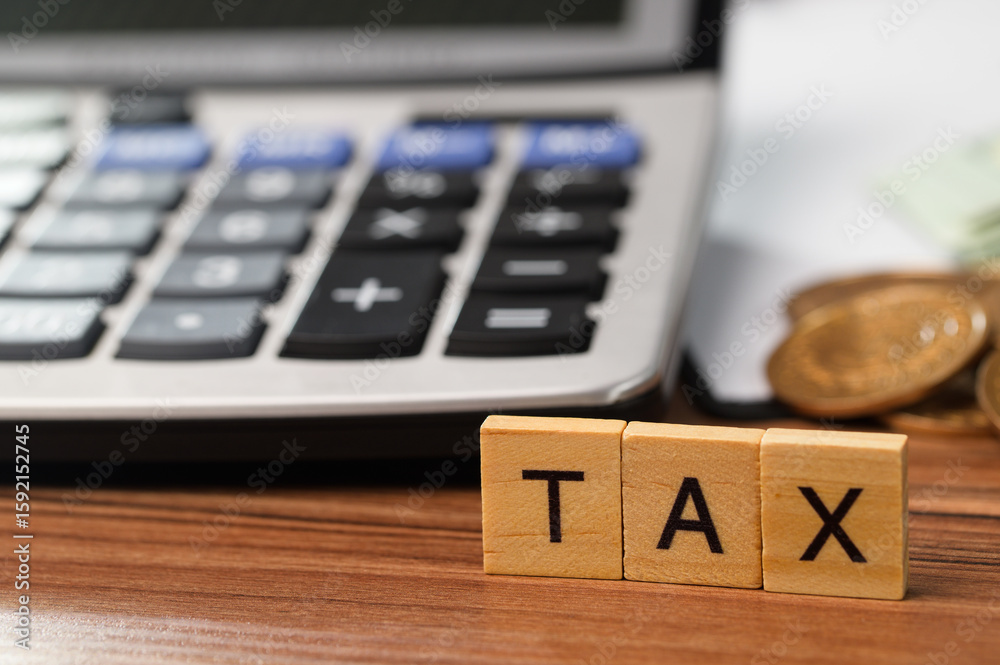 Calculating Taxes with Calculator and Wooden Blocks on Wooden Table Calculating Taxes with Calculator and Wooden Blocks on Wooden Table