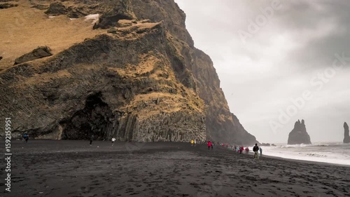 People walk on the black sand beach of reynisfjara in iceland