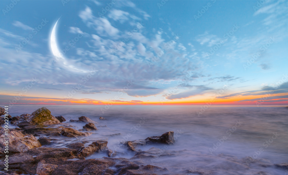 Obraz premium Crescent moon over the sea at amazing sunset - Long exposure image of dramatic sky and seascape with rock at sunset