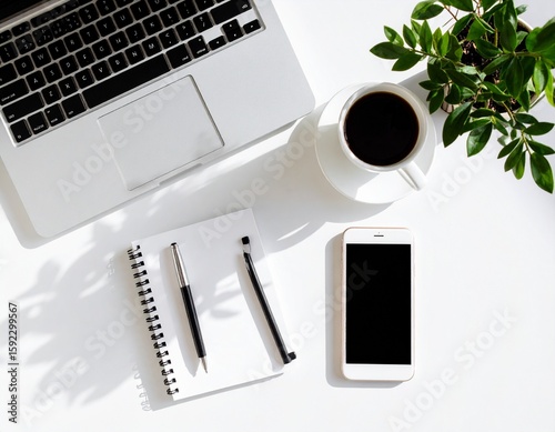 Flat Lay Workspace with Laptop, Smartphone, Coffee Mug, Notepad, and Plant on White Desk