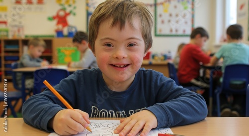 Young boy with Down syndrome drawing happily in bright classroom  