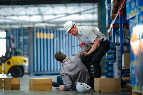 Young worker rushes to help injured senior colleague who fell in warehouse. Team support, safety response, and workplace accident awareness.