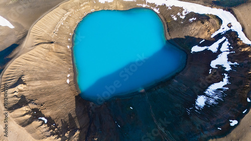 Foto Vivid blue water fills the Krafla crater, surrounded by rugged volcanic terrain and patches of snow