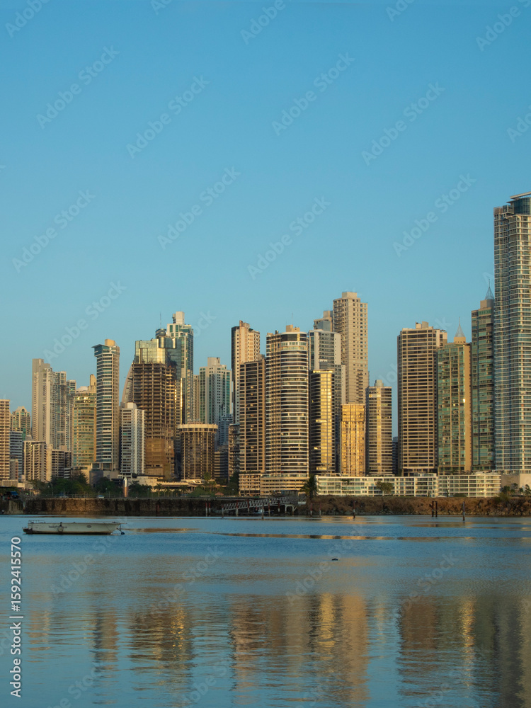 Fototapeta premium Modern skyline of Panama City reflected on coastal waters at sunset