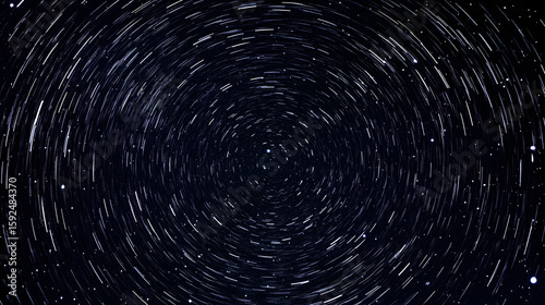 Star trails swirl in a dark night sky creating a circular pattern.