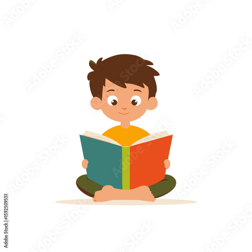 A happy young boy sits cross-legged, engrossed in reading a colorful book.