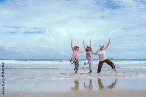 Group of three senior mature retired women on their 60s having fun enjoying together happy walking on the beach smiling playful