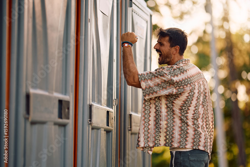Slika na platnu Angry man banging on door of portable toilet while being on open air music festival