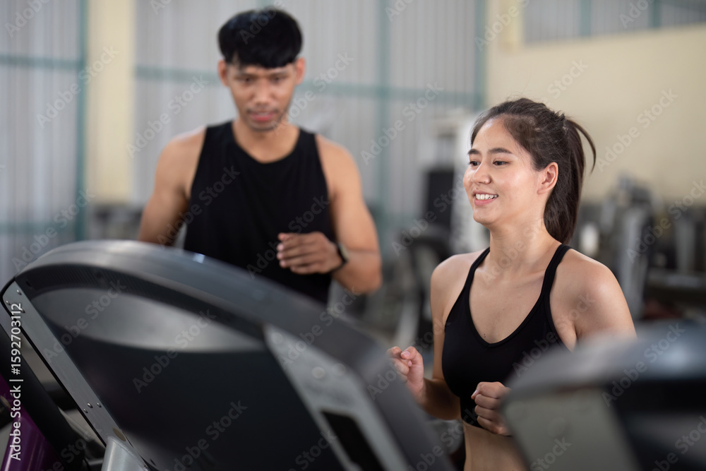 Obraz premium Trainer guiding a young woman on exercise equipment in a gym
