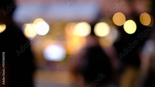 A blurry image of a man and a woman walking together. Scene is mysterious and somewhat romantic, as the people are walking together in the dark