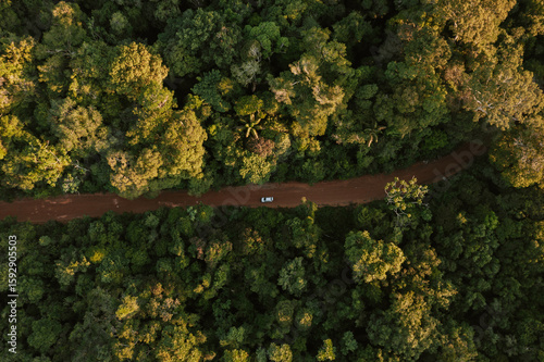 Drohnenaufnahme einer unbefestigten Straße durch den Amazonas-Regenwald in Brasilien auf der ein Auto fährt 1