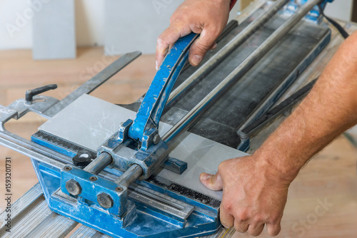 Worker skillfully operates tile cutter, shaping ceramic tiles during home renovation