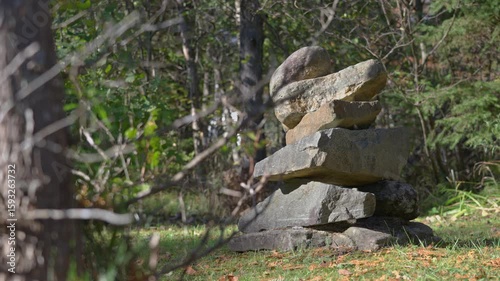 Exploring an inukshuk in the woods with trees and leaves swaying in the wind