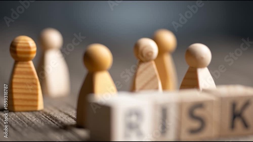 Wooden blocks spelling “RISK” are placed in focus, with blurred wooden pawn figures in the background.