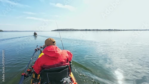 Angler or fishermen in dry suit on motorized pedaling fishing kayak trolling during fishing game tournament in the lake water. Kayak fishing and watersport. Water sport in spring.