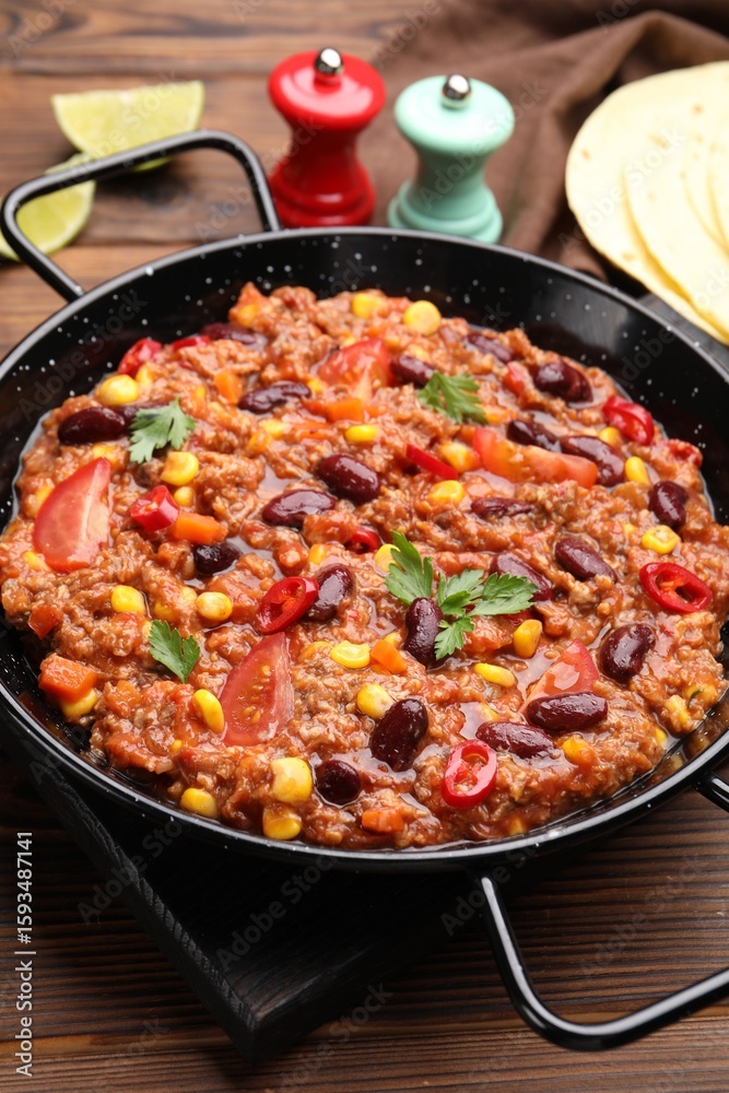 Tasty chili con carne in baking dish on wooden table, closeup Tasty chili con carne in baking dish on wooden table, closeup