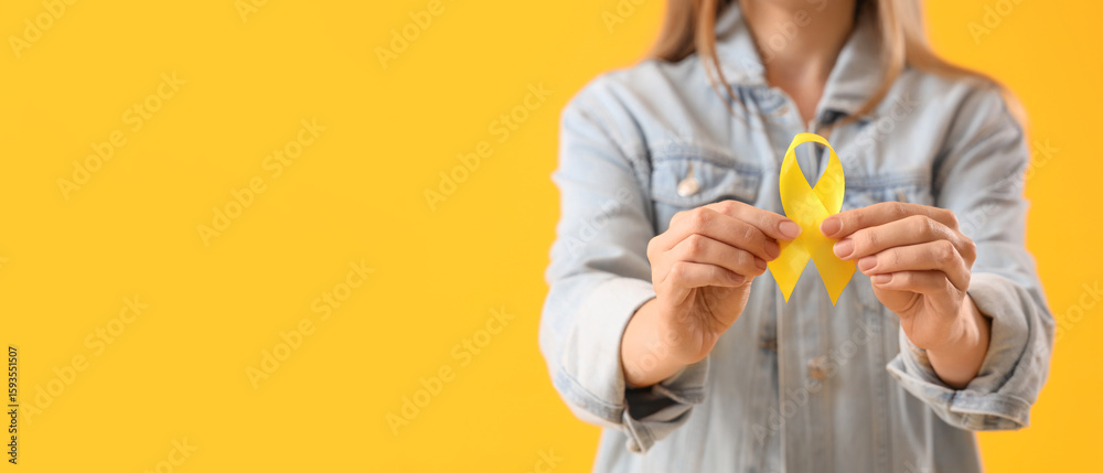 Φωτογραφία Woman with yellow awareness ribbon on color background, closeup