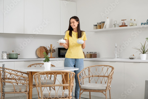 Young woman putting teapot ...