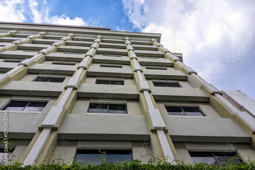 low-angle view of a modern building facade with repetitive windows and a clear sky, showcasing contemporary architecture.