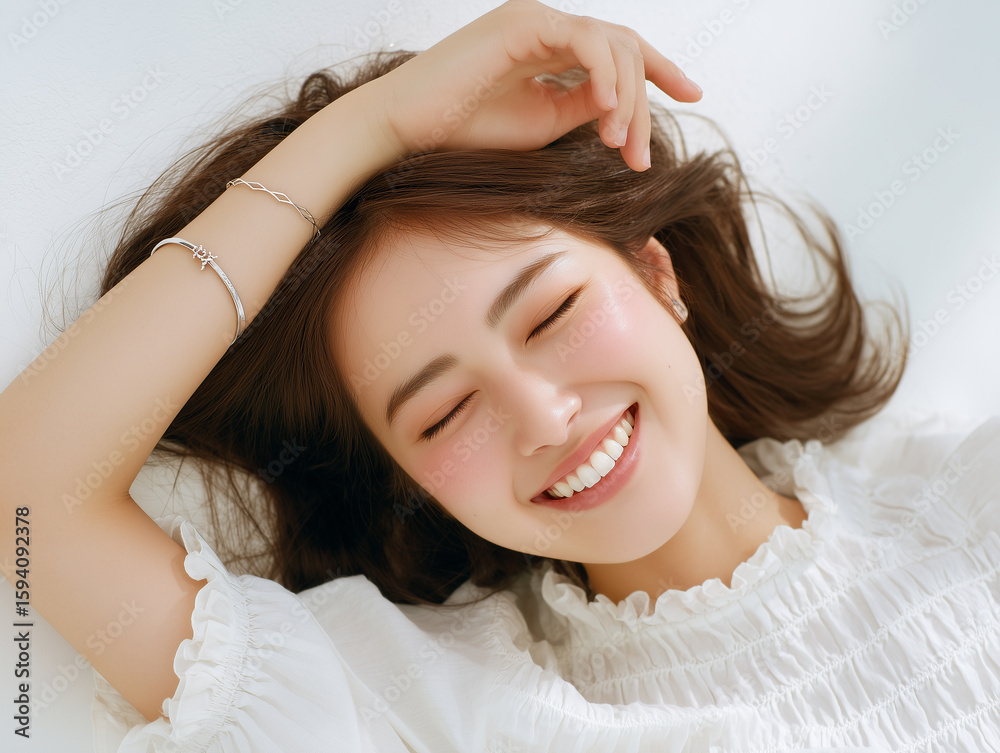 Fototapeta premium リラックスした笑顔が魅力的な寝転んでいる20代日本人女性のナチュラルポートレート（美容 ライフスタイル 広告）
