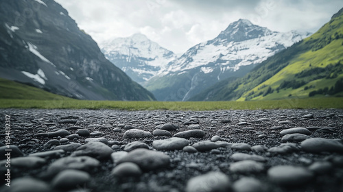 Close-up of rugged mountain rock surface with blurred background showing snow-capped peaks, green slopes, and valley. Scenic natural outdoor landscape ideal for travel, adventure, and product display.