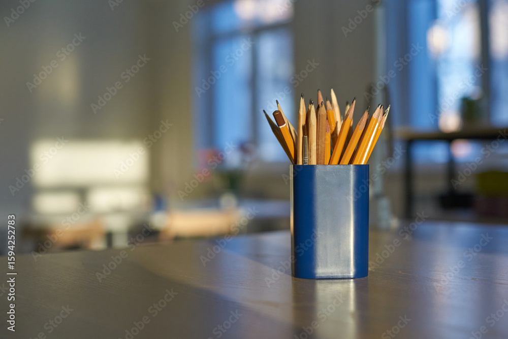 Pencils in blue holder on table in sunlit room near windows. Pencils in blue holder on table in sunlit room near windows.