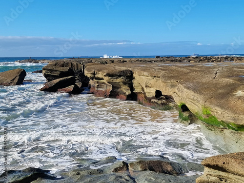 Ocean waves crashing over an eroded rock platform and boulders at Soldiers Point New South Wales Australia. 