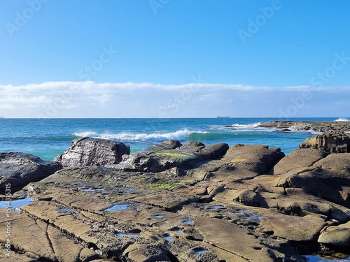 Ocean waves crashing over an eroded rock platform and boulders at Soldiers Point New South Wales Australia. 