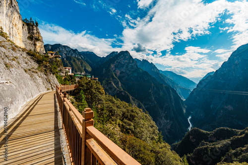 Sunlit mountain walkway overlooking deep gorge in Balagezong, Shangri-La, China