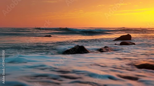 Waves crashing on the shore during a vibrant sunset along the coastline