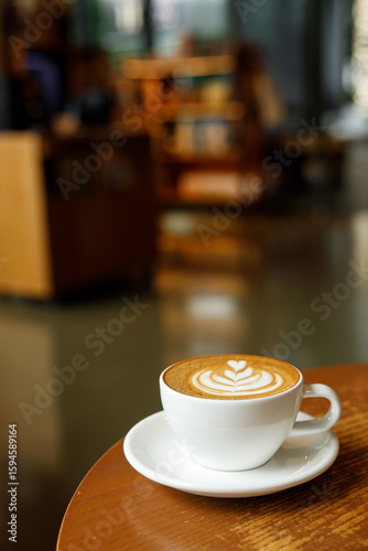 Cup of hot milk latte coffee on table by the window.