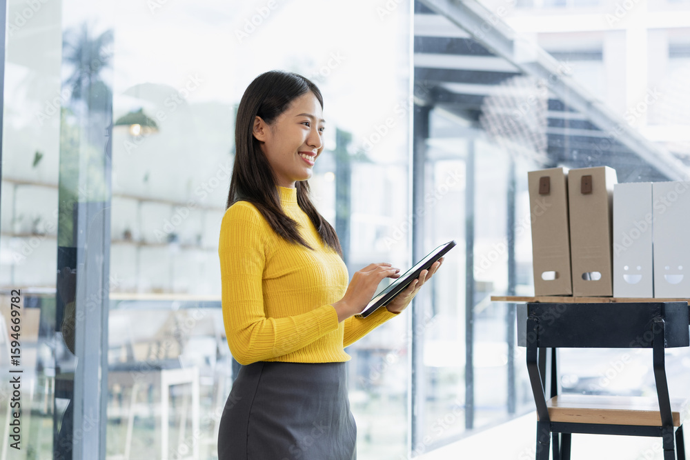 Fototapeta premium Happy young Asian businesswoman holding digital tablet standing in office.