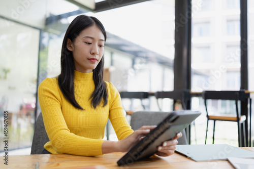 Free Download Happy young Asian businesswoman using digital tablet sitting in office. - GFXLoad