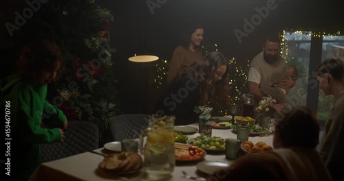 Happy brunette woman with her husband and children sit at the Christmas table during the holiday at home