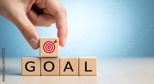 Hand Placing Target Icon on Wooden Block to Complete Word GOAL – Business Planning, Vision, Achievement, Success Strategy Concept