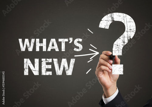 A hand writes whats new next to a large question mark