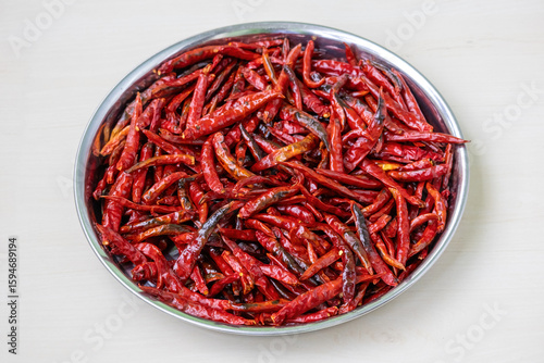 Fototapeta Naklejka Na Ścianę i Meble -  Hot fried red chili peppers on a steel plate, perfect for spicy food. Dry chilies ready for chilli flakes, powder, or blend ingredients. Ideal for hot spice cooking.