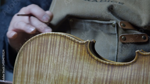 Obraz na plátně Skilled craftsman applying golden brown varnish on wooden violin ribs, hand poli