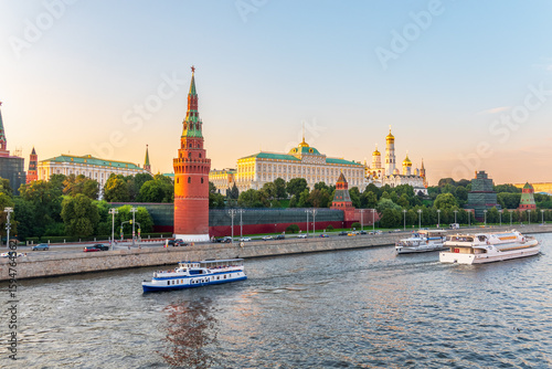 View of Kremlin with Vodovzvodnaya tower, Grand Kremlin Palace from repaired Bolshoy Kamenny Bridge in Moscow city on sunny summer day. Cruise ship sails on the Moscow river