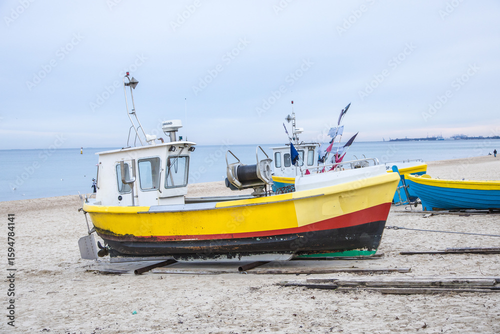 Fototapeta premium Mały żółty rybacki kuter na piaszczystej plaży