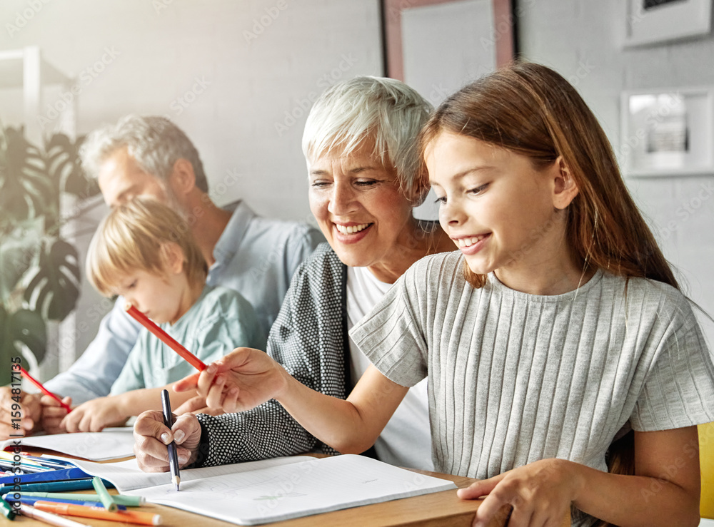 Portrait of grandparents and grandchildren having fun together reading and writing homework at home Portrait of grandparents and grandchildren having fun together reading and writing homework at home