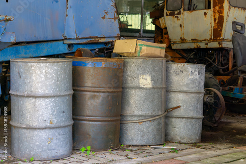 Wallpaper Mural Old metal barrels placed next to rusty machines on a cobbled yard. Scene from an abandoned industrial area Torontodigital.ca
