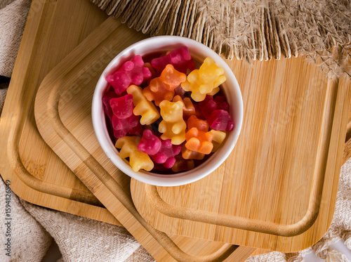 Vitamins and supplements. Multicolored fruit chewy candies or multivitamins in a white bowl on a wooden background. Vitamin supplements in the form of gummy bears.