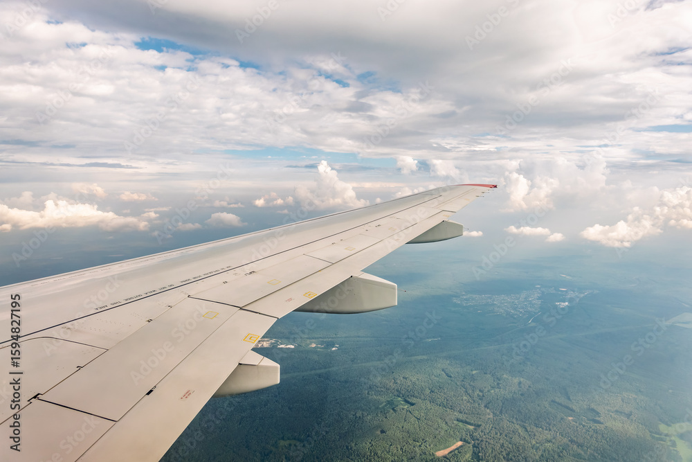 Fototapeta premium View from the airplane window at a beautiful cloudy sky and the airplane wing