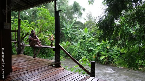 A woman sitting on wooden balcony by the river