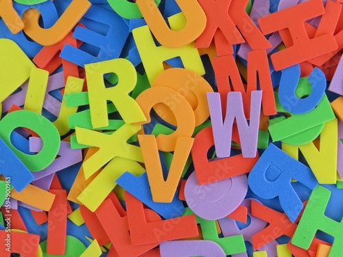Multicolored eva foam letters scattered on blue background. Abstract background with letters of the alphabet.
