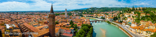 View of Ponte Pietra, Verona’s ancient Roman stone bridge crossing the Adige River under a clear sunny sky with historic buildings nearby