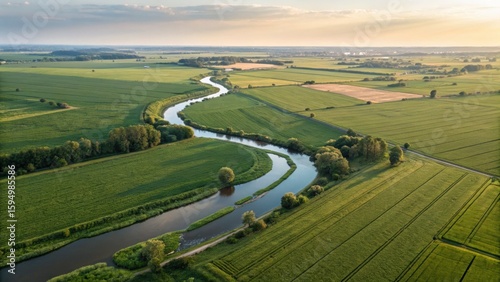 Aerial view of winding river through green fields at sunset, showcasing rural landscape